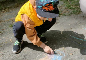 Chłopiec rysuje używając kredy