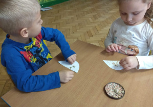 Dzieci naklejają ziarenka na papier.