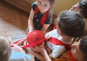 Dzieci w grupie przenoszą piłkę