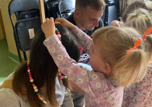 Dziewczynka nakłada korale swojej mamie