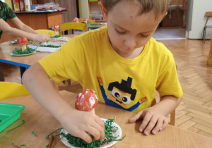 Chłopiec układa mech z papieru