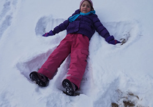 Dziewczynka robi aniołka na śniegu