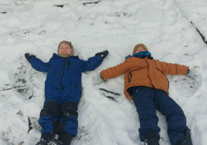 Dzieci robią aniołki na śniegu