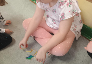 Dziewczynka układa imię z patyczków.