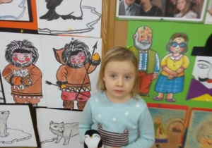 Dziecko pozuje na tle obrazków z pingwinem.