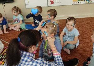 Nauczycielka maluje dziecku twarz