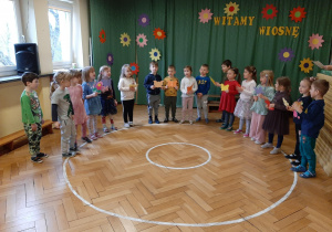 Zdjęcie przedstawia grupę dzieci prezentujących wiersz o matematyce.