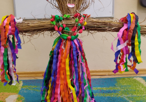 Zdjęcie przedstawia kukłę - Marzannę wykonaną ze słomy i kolorowej bibuły