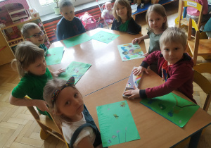 Dzieci wykonują pracę plastyczną na zielonych kartach rysują Panią Wiosnę