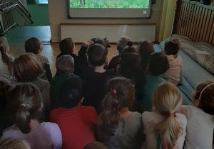 Grupa dzieci ogląda film edukacyjny o zwiastunach wiosny.