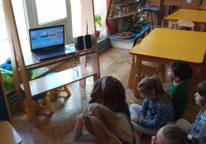Dzieci oglądają film edukacyjny o Polsce na laptopie.