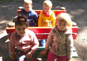 Dzieci bawią się w drewnianym samochodzie.