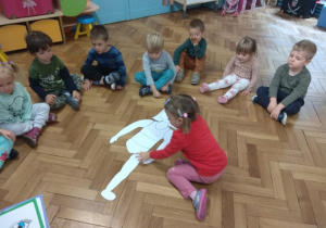 Dzieci układają postać dziewczynki z części ciała wyciętych z papieru.