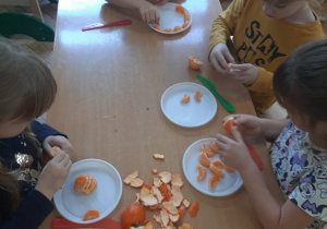 Dzieci obierają mandarynki.
