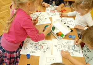 Dzieci malują obrazek robota.