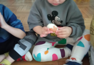 Dziewczynka obiera jajko ze skorupki.