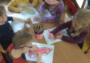 Dzieci kolorują kredki przy stoliku.