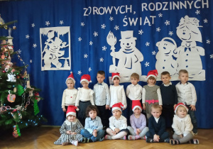 Grupa dzieci ubrana na galowo na tle zimowej dekoracji
