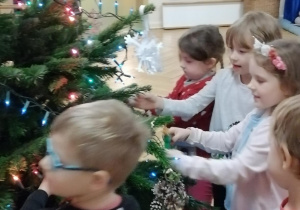 Dzieci przystrajają ozdobami drzewko