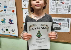 Dziewczynka trzyma dyplom za udział w konkursie.