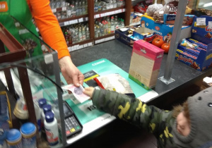 Chłopiec płaci w sklepie za zakupy.