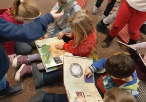 Grupa dzieci przegląda książki z literatury dziecięcej.