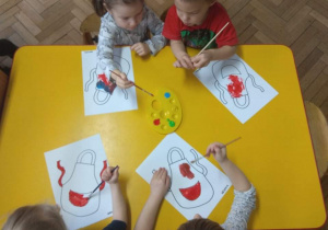 Dzieci malują farbami fartuszki.
