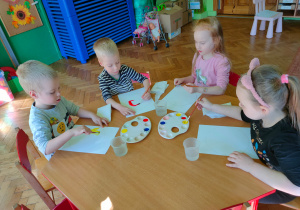 Dzieci malują farbami na kartce.