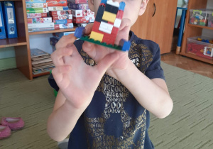 Chłopiec poakzuje budowlę z lego