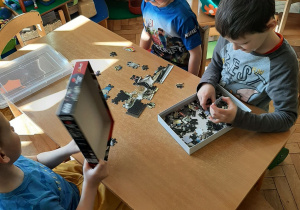 Chłopcy układają puzzle.