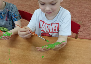 Dziecko maluje zieloną farbą dłoń