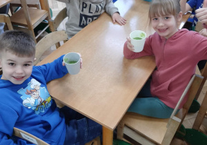 Dzieci piją zielony koktajl.
