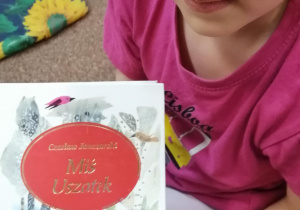 Dziewczynka pokazuje książkę o Misiu Uszatku