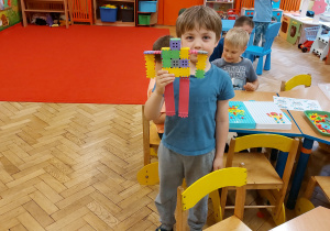 Dziecko pokazuje budowlę z klocków.