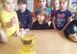 Dzieci wpuszczają kolorowy barwnik spożywczy do naczynia