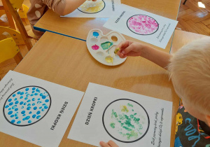 Dzieci malują farbami kropki przy użyciu palców.