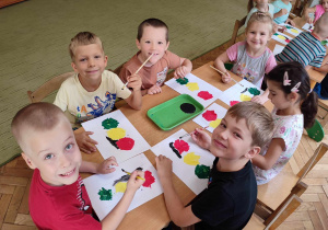Grupa dzieci maluje czarną farbą sygnalizator.