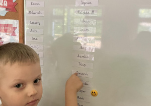 Chłopiec pokazuje swoje imię na tablicy.