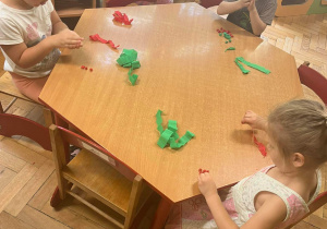Dzieci robią kulki z zielonej i czerwonej bibuły.