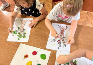 Dzieci malują jesienne liście patyczkami higienicznymi.
