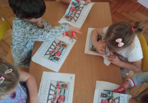 Dzieci tną obrazek na części, tworząc puzzle