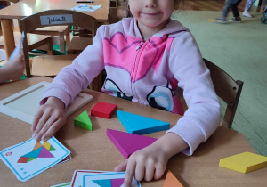 Dziewczynka układa drewniana układankę.
