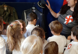 Zdjęcie przedstawia dzieci oglądające mundur wojskowy.