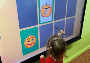 Dzieci grają w dyniowe memory na tablicy interaktywnej