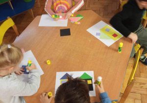 Dzieci układają domy z figur geometrycznych