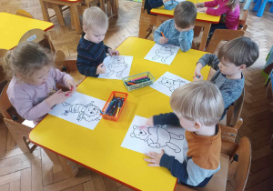 Dzieci kolorują rysunek Kubusia Puchatka.