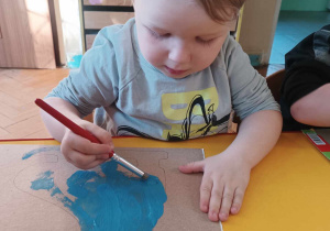 Chłopiec maluje łyżwę niebieską farbą.