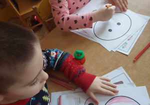 Dzieci kolorują rysunek świnki.