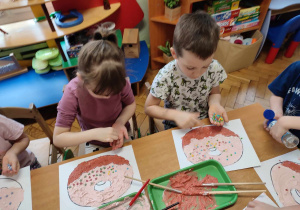 Dzieci malują pączka piankową farbą .