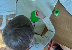 Dziecko maluje serce na ekotorbie.